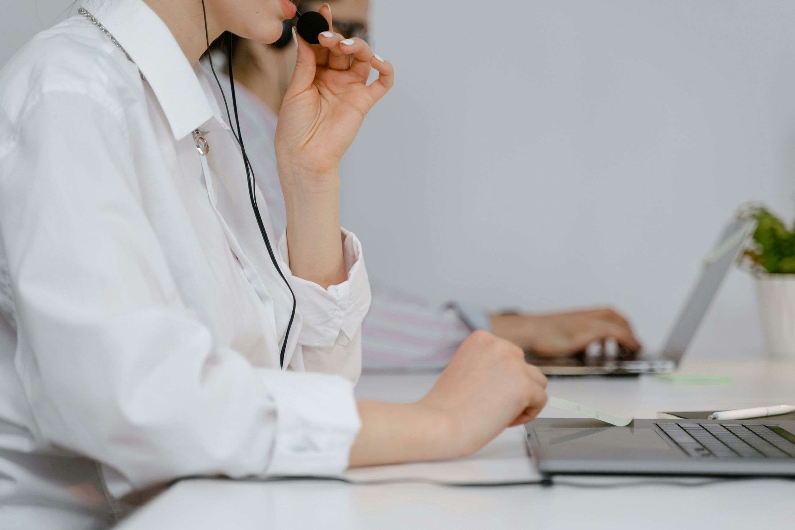 Mulher usando um headset enquanto trabalha em um notebook, representando a importância de uma gestão eficiente de Telecom. Evite 5 erros comuns e otimize sua operação!